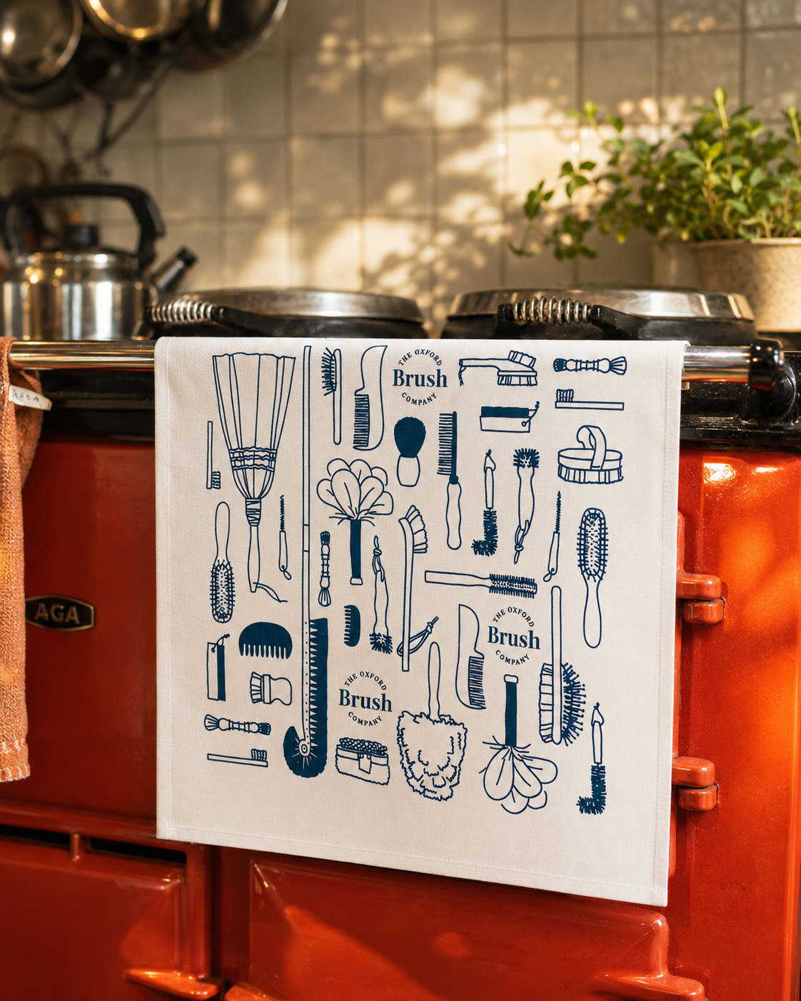 Tea towel with brush design hanging on a red Aga range cooker.